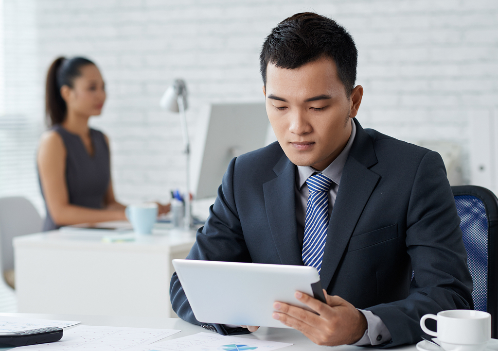 Man in formal wear working on a tablet PC at an office desk